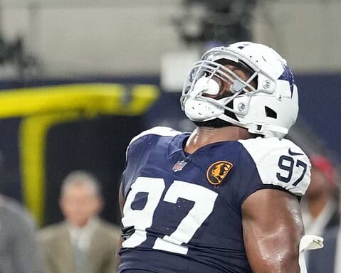 High school football player wearing Dallas Cowboys helmet and jersey number 97 on the field.
