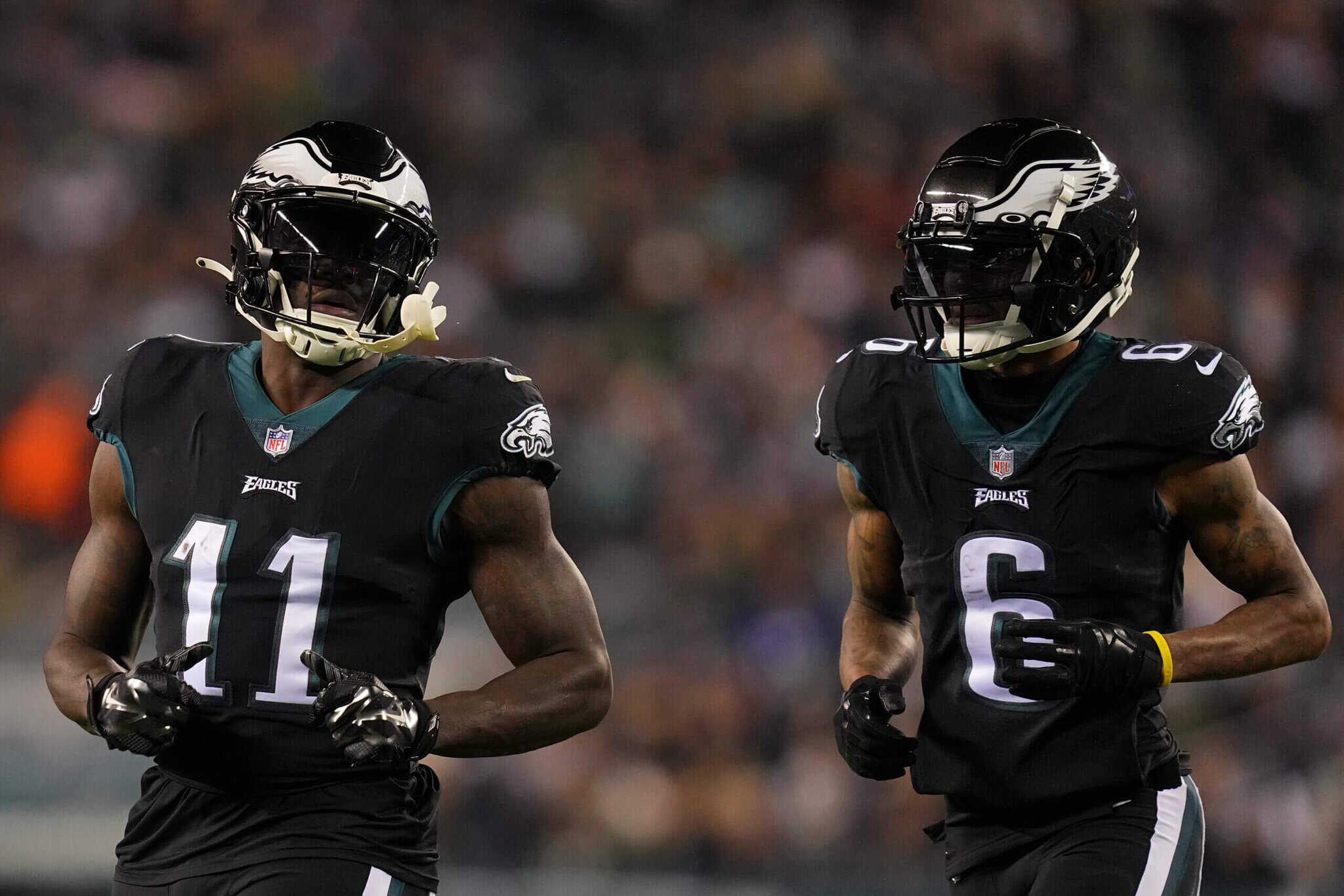 NFL football players from the Philadelphia Eagles team wearing black jerseys and helmets during a game, showcasing players number 11 and 6, in action on the field.