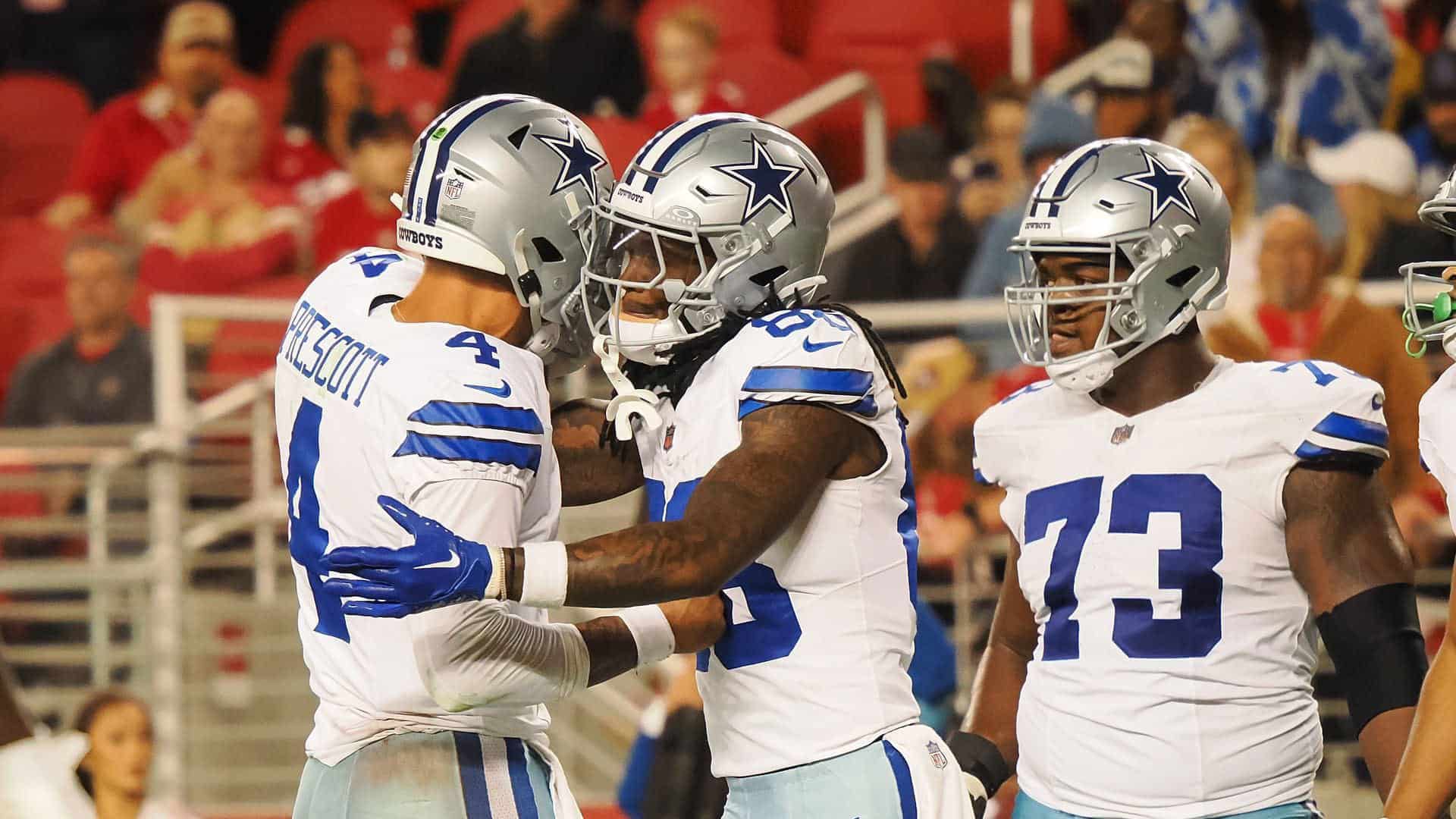 Celebrating Dallas Cowboys football players on the field during a game, showcasing team spirit, camaraderie, and athletic performance, with fans in the background.