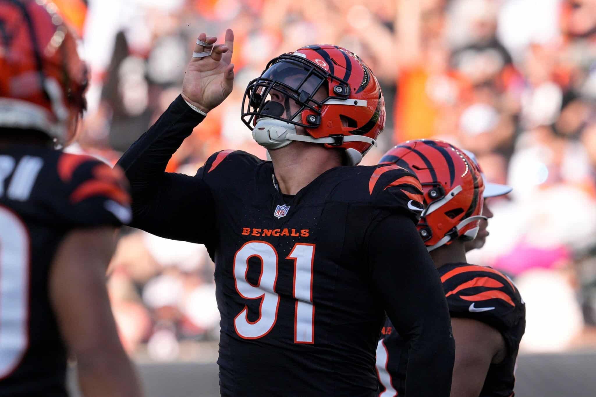 Cincinnati Bengals football player celebrating on the field during an NFL game, wearing black and orange uniform, helmet, and number 91.