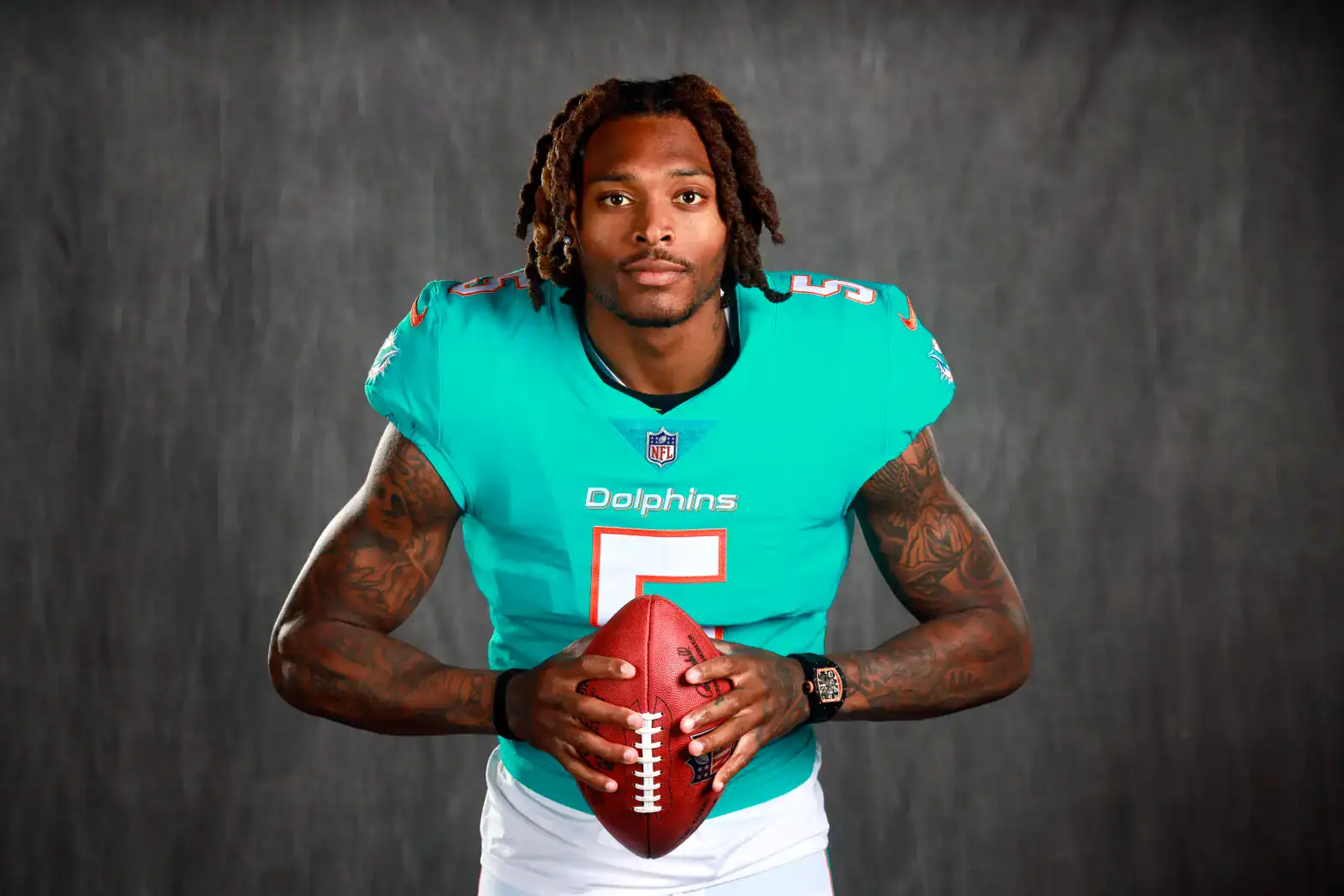 Cedric Wilson Jr. in Miami Dolphins football uniform holding a football, showcasing a player profile from Inside The Star, with a dark gray background.