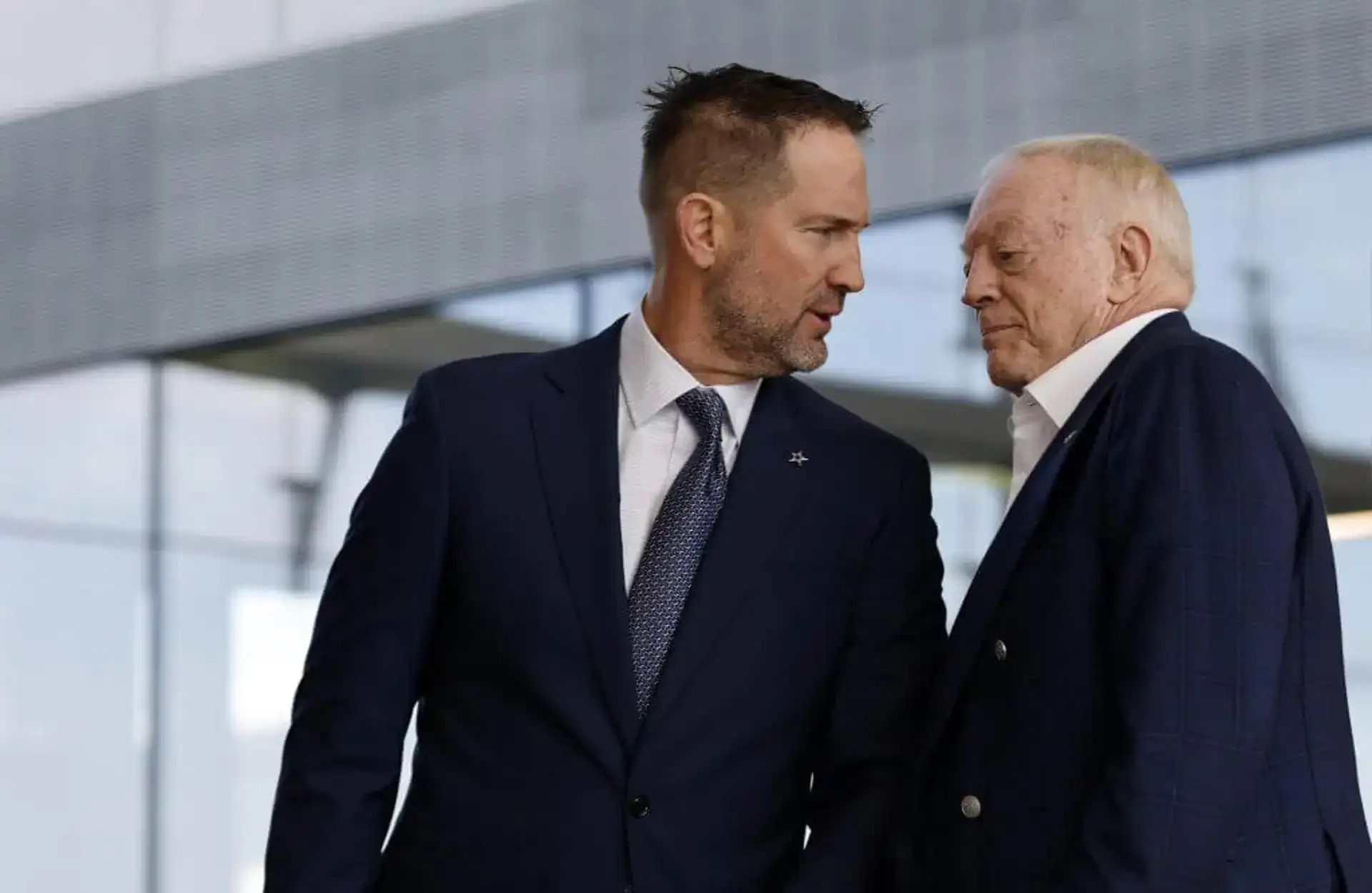 Focused Dallas Cowboys executives in formal suits engaging in a close discussion outside the stadium, emphasizing team management, leadership, and NFL team operational insights.