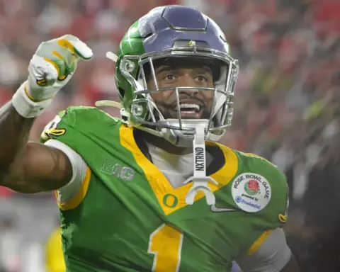 Vikings football player celebrating on the field in green uniform with a helmet and gloves, during a game, representing the Minnesota Vikings team, inside The Star sports complex.