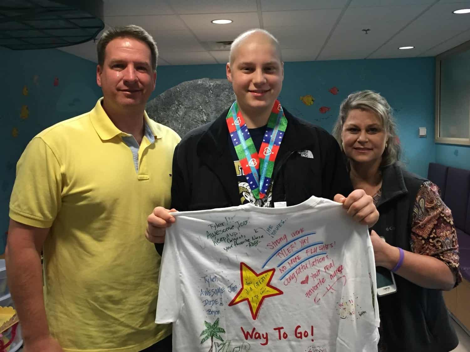 Happy young athlete with medals and signed shirt at Inside The Star event, celebrating sports achievements and community support.