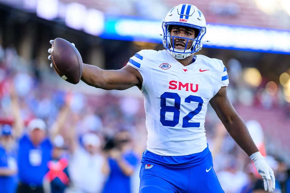 Highlights of a college football player in action, wearing a white and blue uniform with the number 82, holding a football on the field during a game at SMU.