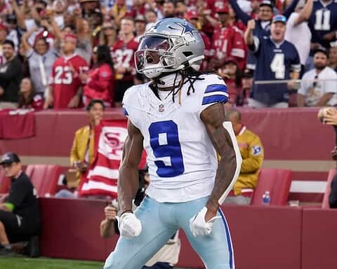 Dallas Cowboys wide receiver celebrating during a football game at Levi's Stadium in San Francisco. The player is wearing jersey number 9, with a silver helmet and white and blue uniform, surrounded by fans and team staff.