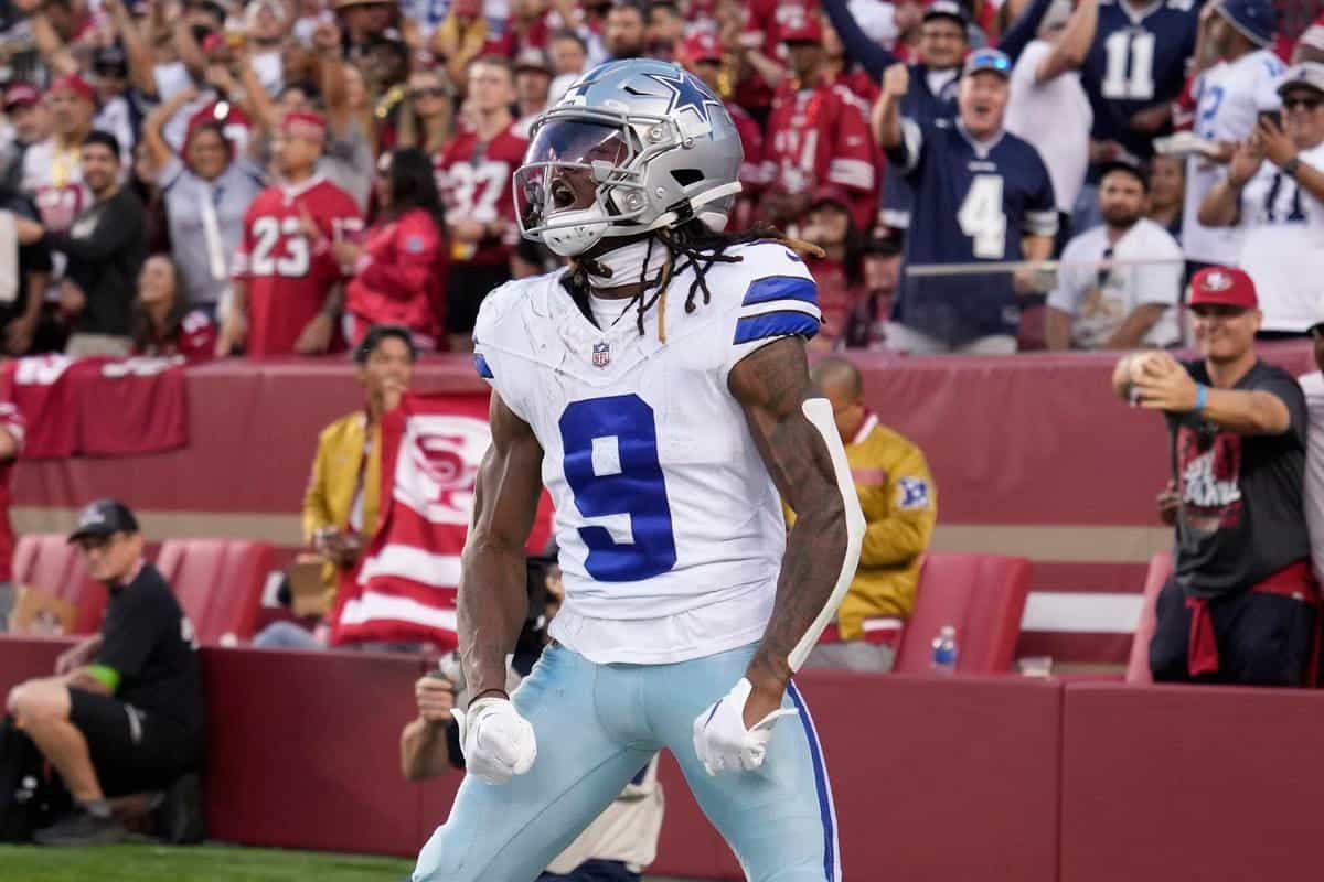 Dallas Cowboys wide receiver celebrating during a football game at Levi's Stadium in San Francisco. The player is wearing jersey number 9, with a silver helmet and white and blue uniform, surrounded by fans and team staff.