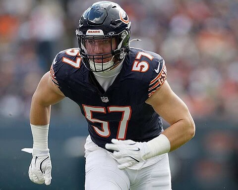 Fast football player wearing a Chicago Bears jersey number 57 during game, on the field with blurred crowd background.