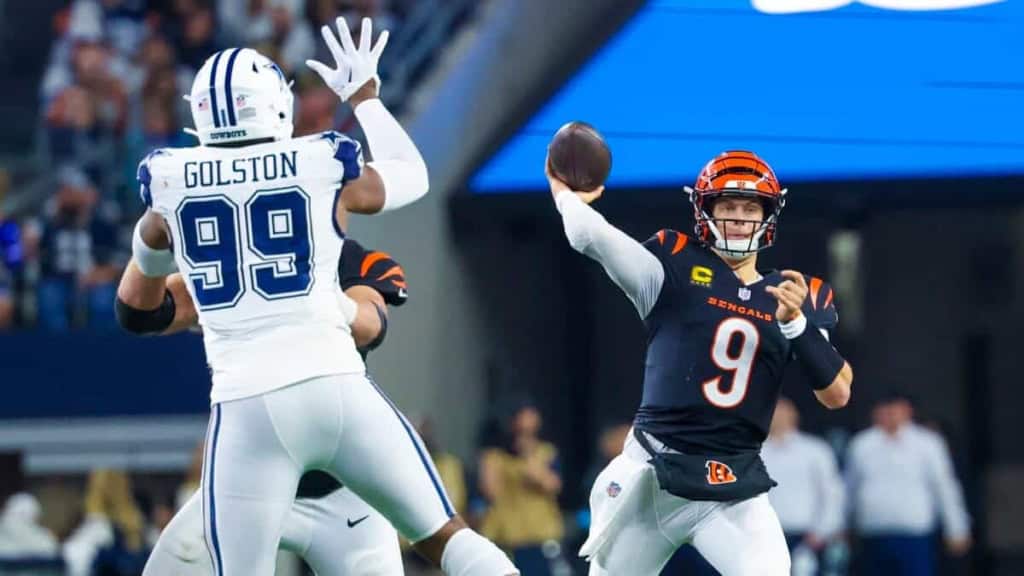Cincinnati Bengals quarterback throwing a football against the Dallas Cowboys defense during an NFL game. Focus on action-packed moment showcasing team rivalry and football excitement.