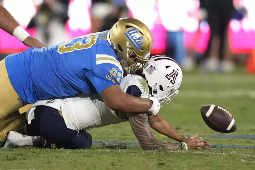 UCLA football player tackled during game on the field, football in mid-air, showcasing intense action and athleticism, Inside The Star sports coverage.
