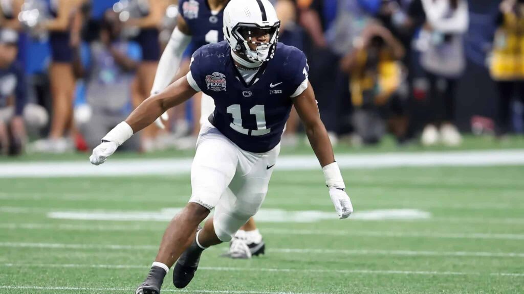 Athletic football player wearing a navy blue jersey and white helmet on the field during a game.