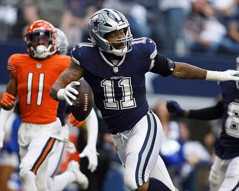 Dallas Cowboys running back with the football during an NFL game, surrounded by defenders from opposing team, in a competitive play moment.