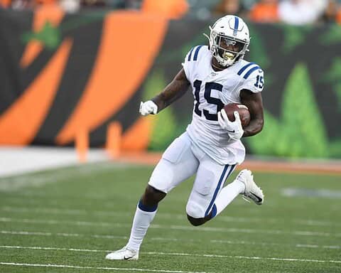 Fast-paced football player in white and blue uniform running with the ball on the field, representing the Dallas Cowboys.