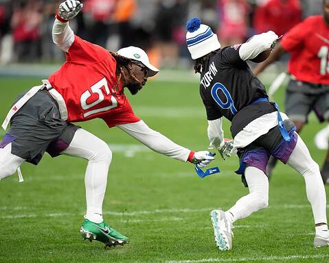 High-energy football game with players in action on the field, focusing on NFL athletes in red and black uniforms during a competitive play.