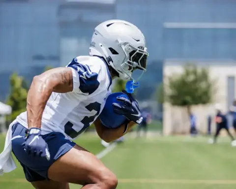 Fast-paced football player wearing Dallas Cowboys uniform during practice or training on outdoor field.
