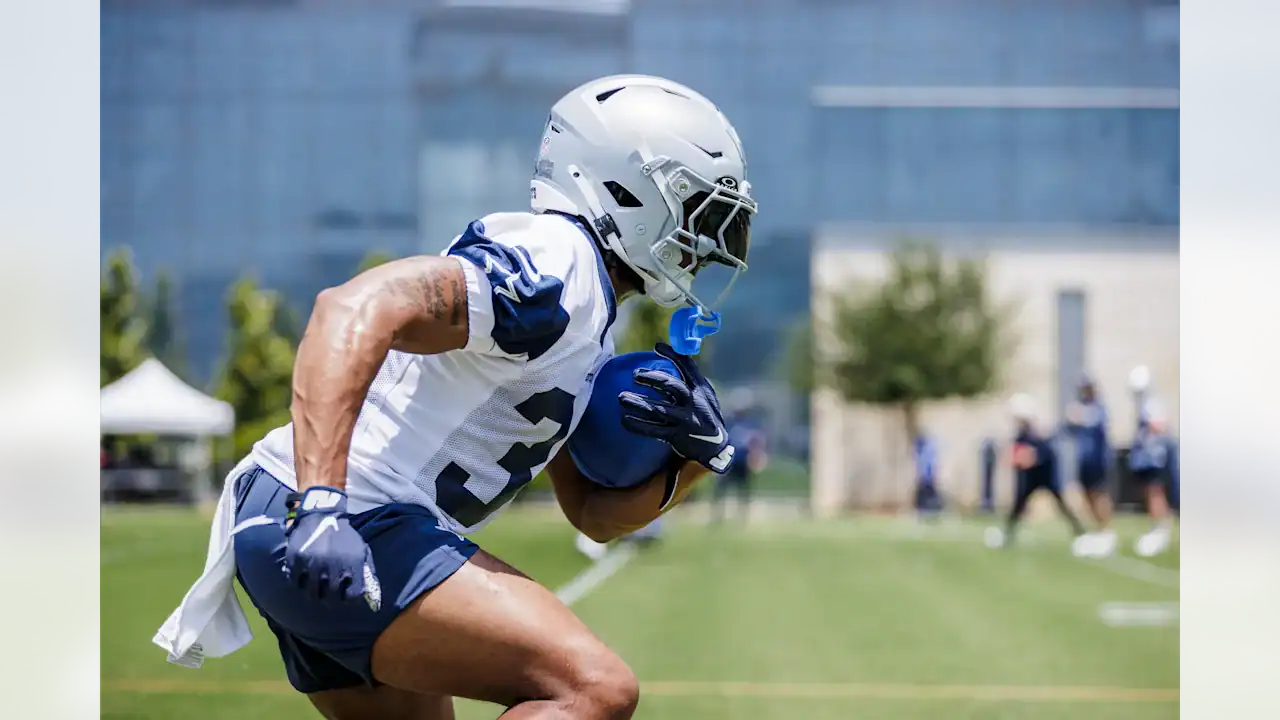 Fast-paced football player wearing Dallas Cowboys uniform during practice or training on outdoor field.