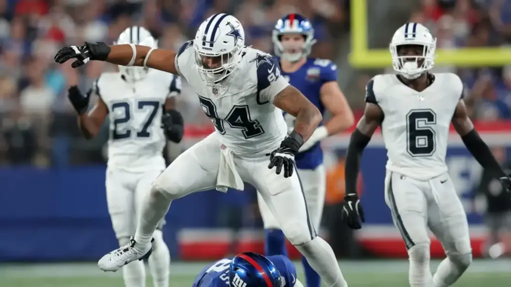 A Dallas Cowboys linebacker tackles a New York Giants player during an NFL game, showcasing football action, team rivalry, and game intensity at the stadium.