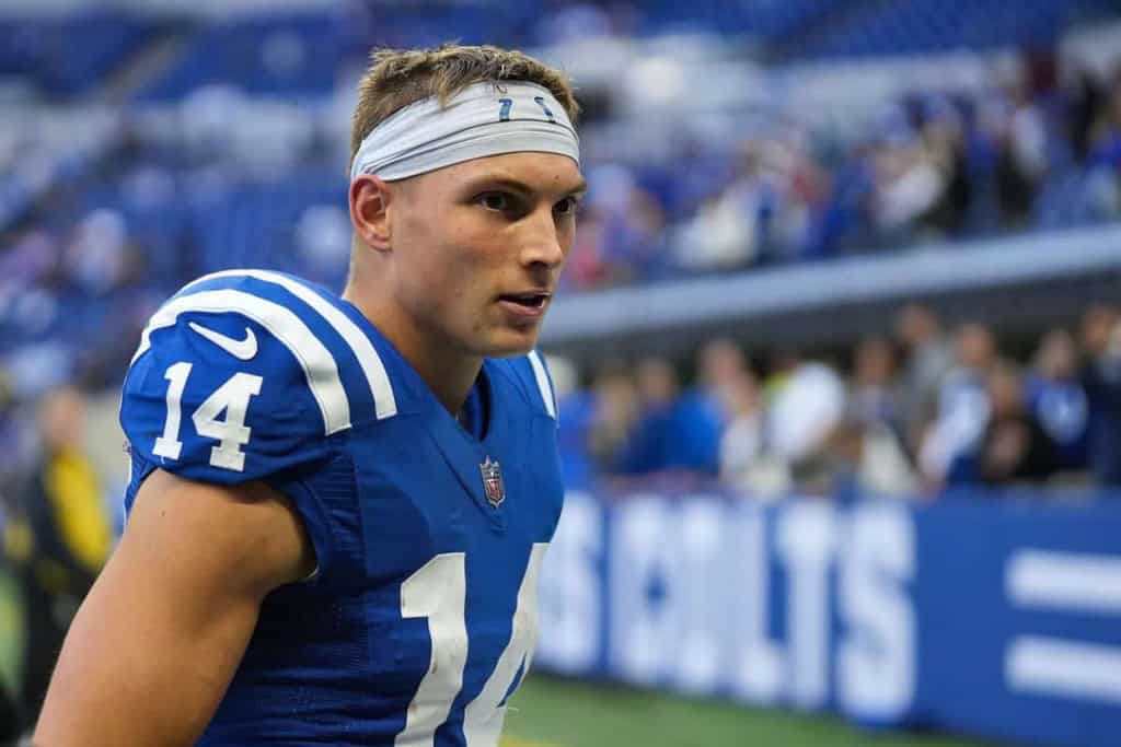 Young football player wearing a blue jersey and white headband, standing on the field during a game at AT&T Stadium.