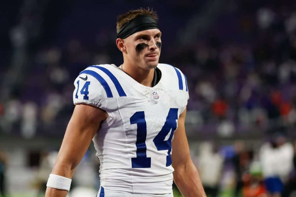 Indianapolis Colts football player standing on the field during a game, wearing jersey number 14, with black eye paint, focused expression, stadium background.