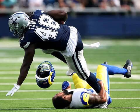 Aggressive football player in Dallas Cowboys uniform making a tackle on opponent during a game, showcasing NFL action, sports competition, and athletic effort.