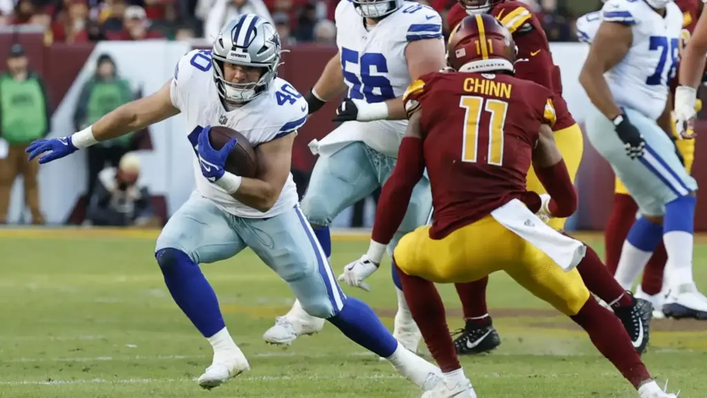 Running back carrying football during NFL game between Dallas Cowboys and Washington Commanders.