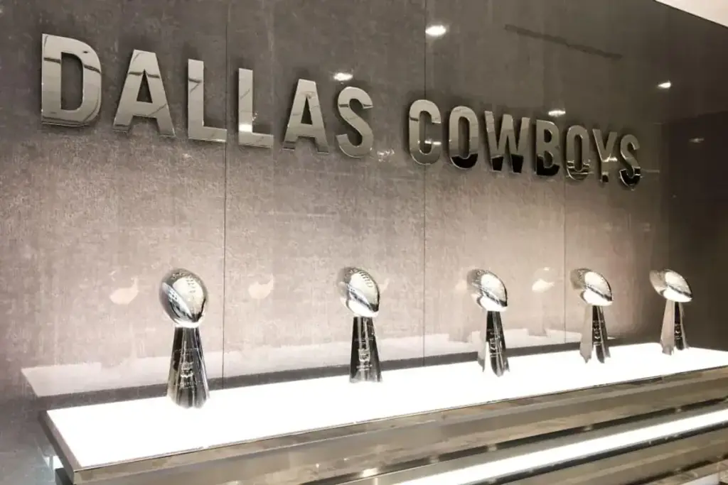 Dallas Cowboys awards display with silver trophies on a white shelf, showcasing the team's achievements and history at Inside The Star.