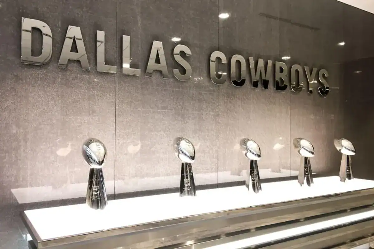 Dallas Cowboys awards display with silver trophies on a white shelf, showcasing the team's achievements and history at Inside The Star.