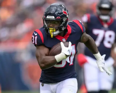 Running back in Houston Texans uniform holding a football during a game.