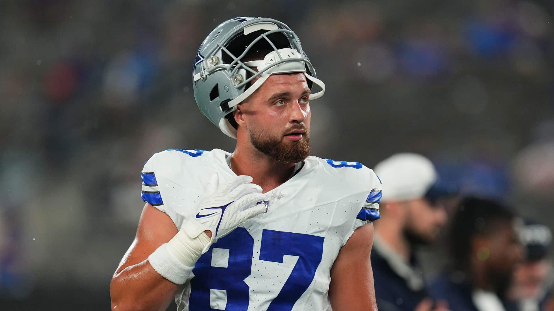 NFL player in uniform with helmet on, representing Dallas Cowboys, on the field during a game or practice, focused and ready.