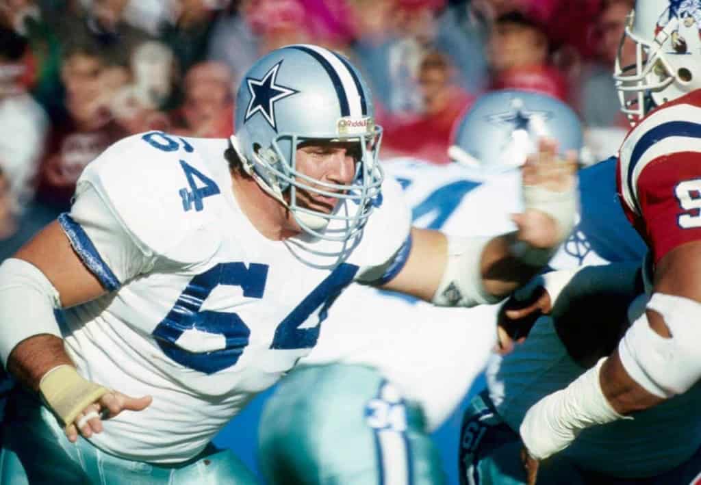 Dallas Cowboys linebacker during an NFL game, wearing white jersey and helmet, in an intense action moment on the field.