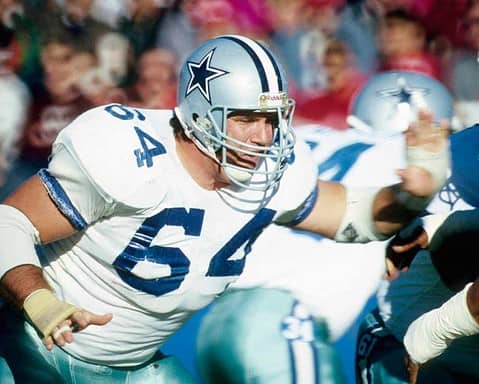 Dallas Cowboys linebacker during an NFL game, wearing white jersey and helmet, in an intense action moment on the field.