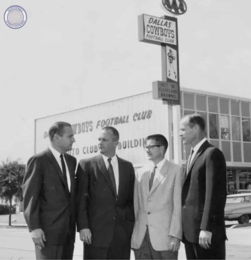 Men in suits standing outside Dallas Cowboys Football Club building, vintage black-and-white photo.