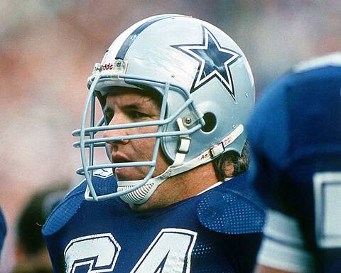 Dallas Cowboys football player wearing helmet during game, close-up action shot with team logo, intense focus, football gear, and team spirit, inside the star stadium.