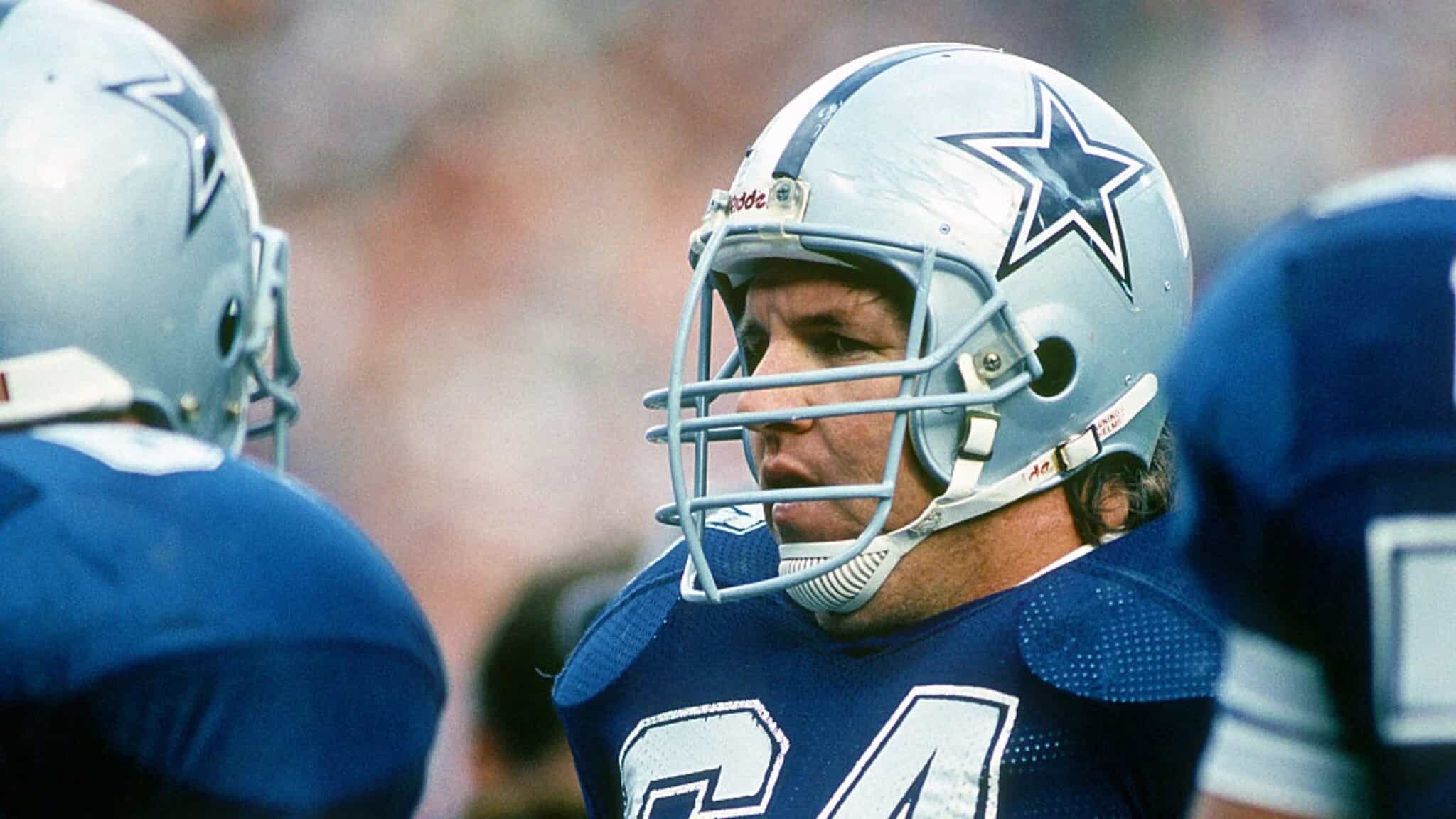 Dallas Cowboys football player wearing helmet during game, close-up action shot with team logo, intense focus, football gear, and team spirit, inside the star stadium.