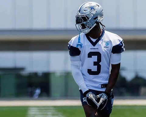 Game-ready Dallas Cowboys football player wearing uniform and helmet during practice or game on the field.