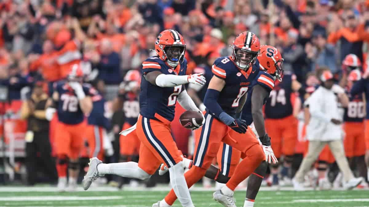 Young football players celebrating on the field during a game, wearing orange and navy uniforms, representing the Dallas Cowboys, inside the star, NFL football, sports action, team victory.