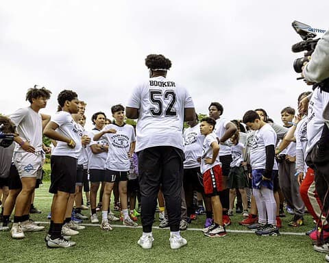 Youth football team huddle with coach outdoors at the Inside The Star sports camp, promoting football skills, teamwork, and athletic development for young players.
