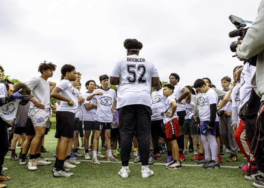 Youth football team huddle with coach outdoors at the Inside The Star sports camp, promoting football skills, teamwork, and athletic development for young players.