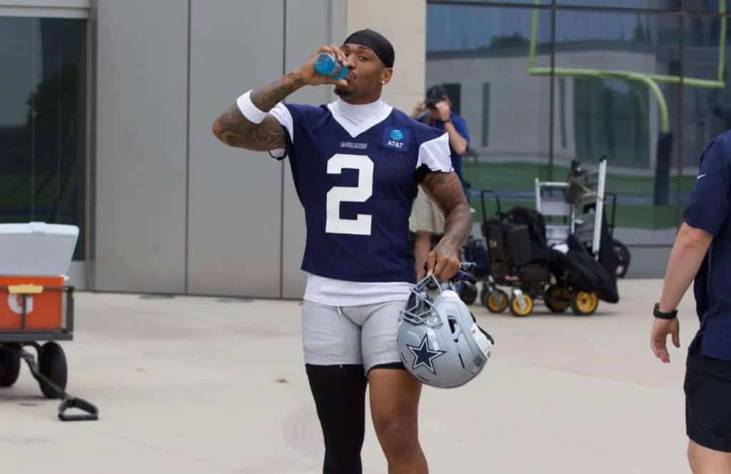 Cowboys' S Juanyeh Thomas, wearing a blue #2 jersey, takes a drink of water while walking out to Cowboys' practice at 2025 OTAs