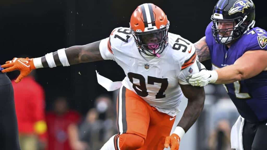 Explosive NFL football tackle between Cleveland Browns and Baltimore Ravens players during game. Action shot capturing defensive play on the field, showcasing intensity and athleticism.
