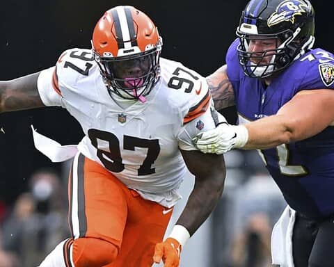 Explosive NFL football tackle between Cleveland Browns and Baltimore Ravens players during game. Action shot capturing defensive play on the field, showcasing intensity and athleticism.