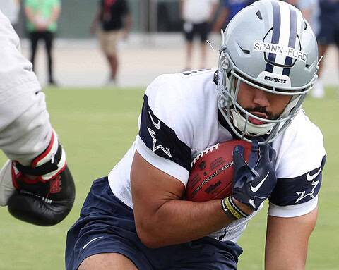Football player holding football during practice at the Dallas Cowboys training camp.