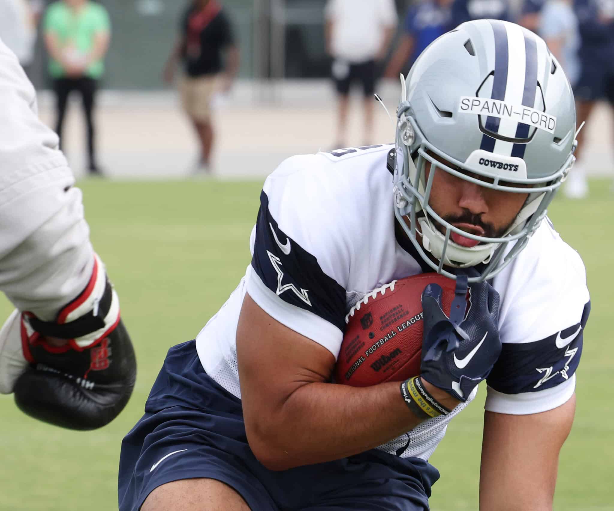 Football player holding football during practice at the Dallas Cowboys training camp.