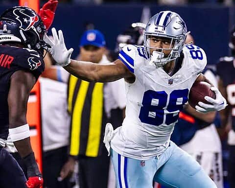 Dallas Cowboys TE Brevyin Spann-Ford, wearing a white #89 jersey carries the football and attempts to stiff arm a defender