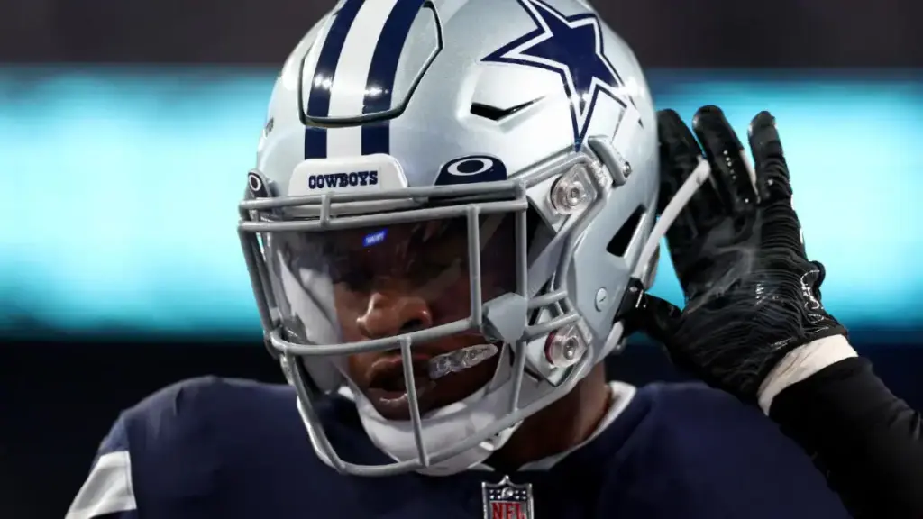 Dallas Cowboys football player adjusting helmet during game, close-up image showcasing team gear and focus on sports action.