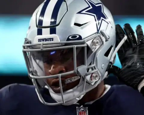 Dallas Cowboys football player adjusting helmet during game, close-up image showcasing team gear and focus on sports action.
