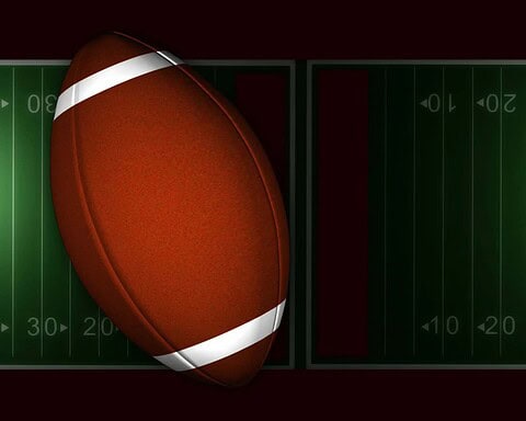 Faded American football resting on a football field with yard lines, illustrating Inside The Star's focus on Dallas Cowboys news and NFL updates.