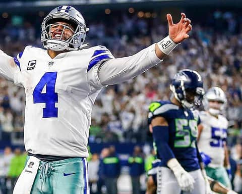 A quarterback celebrating with open arms during an NFL game for the Dallas Cowboys, wearing a white jersey with the number 4, on the field with excited fans in the background.