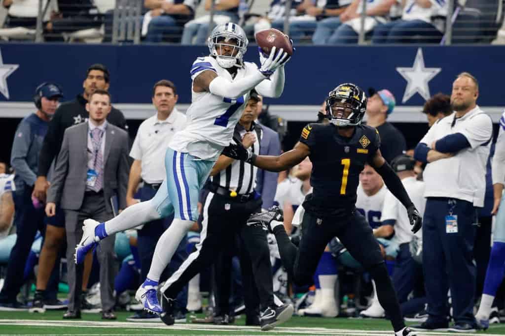 C.D. Lamb catches a pass during an NFL game, showcasing Dallas Cowboys' offensive play. The action highlights athleticism, teamwork, and game strategy in professional football.