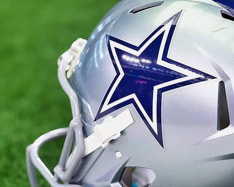Dallas Cowboys football helmet with star logo on green field, NFL game gear, professional football equipment, American football helmet, sports team apparel, Inside The Star coverage.